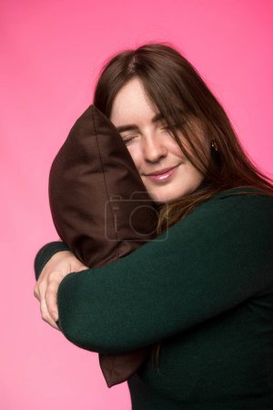 Foto de Una mujer de apariencia eslava abraza una almohada con los ojos cerrados - Imagen libre de derechos