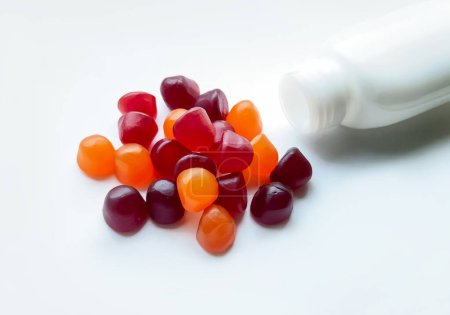 Photo for Group of red, orange and purple multivitamin gummies with the bottle isolated on white background. Healthy lifestyle concept.. - Royalty Free Image