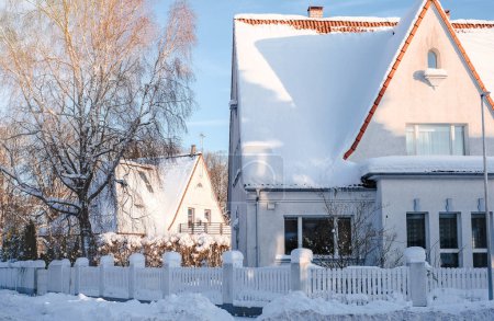 Winter fairy-tale landscape on the street with houses with a triangular roof and roads covered with a lot of snow.