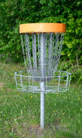 Téléchargez les photos : Un panier de golf à disques avec des chaînes se trouve sur un terrain herbeux, entouré d'arbres. - en image libre de droit