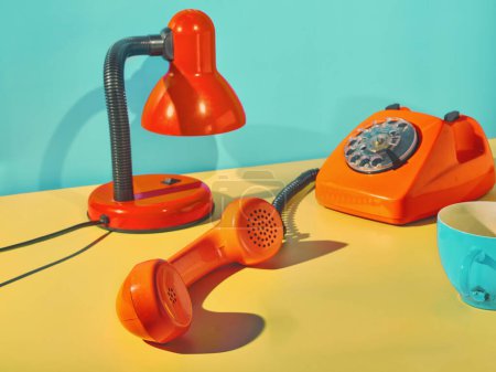 Vintage orange phone, table lamp and coffee cup