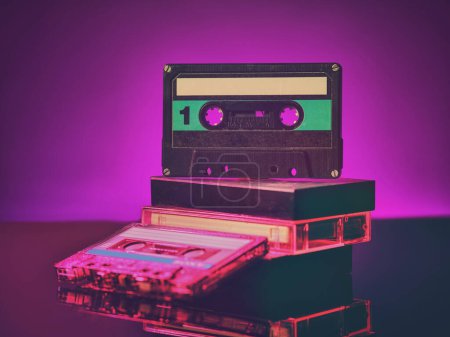 Téléchargez les photos : Vintage audio cassettes on the table in neon light - en image libre de droit