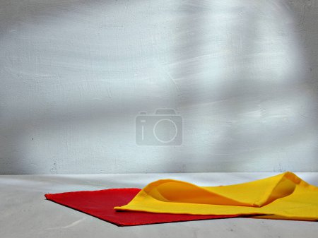 Téléchargez les photos : Vêtements rouges et jaunes avec ombre sur mur blanc texturé - en image libre de droit