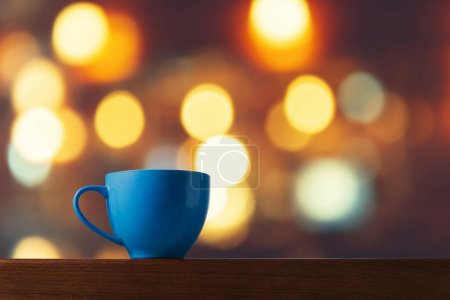 Photo for Blue Ceramic Cup on Wooden Table with Bokeh Background Lights - Royalty Free Image