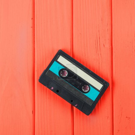 Téléchargez les photos : Ruban de cassette audio sur fond en bois rouge - en image libre de droit