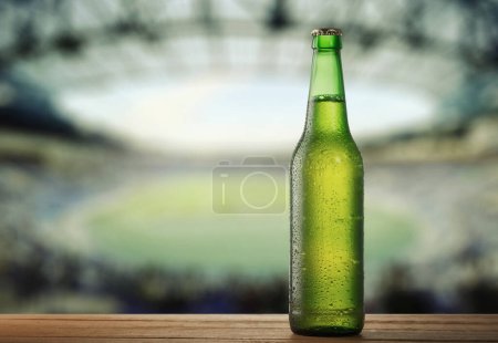 Cold green Beer Bottle on Wooden Surface with Stadium on Background