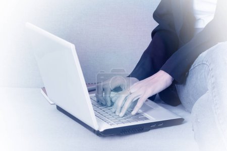 Téléchargez les photos : Photo couleur monotone d'une femme d'affaires assise sur le banc tapant le clavier de l'ordinateur portable. - en image libre de droit