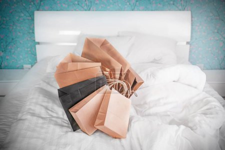 Téléchargez les photos : Des sacs artisanaux reposent sur le lit dans la chambre. Concept commercial - en image libre de droit