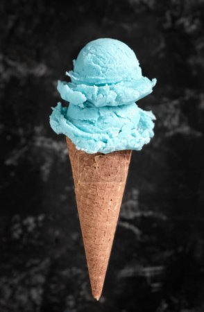 Téléchargez les photos : Crème glacée bleue dans un cône de gaufre sur un fond gris - en image libre de droit