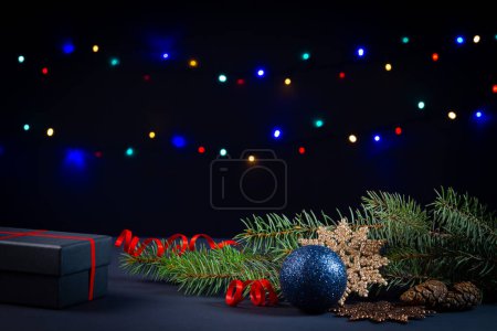 Foto de Árbol de Navidad, decoraciones, luces y una caja de regalo sobre un fondo negro - Imagen libre de derechos