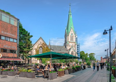 Téléchargez les photos : Kristiansand, Norvège - 15 août 2022 : Les gens profitent d'une journée ensoleillée au centre-ville avec la cathédrale en arrière-plan. - en image libre de droit