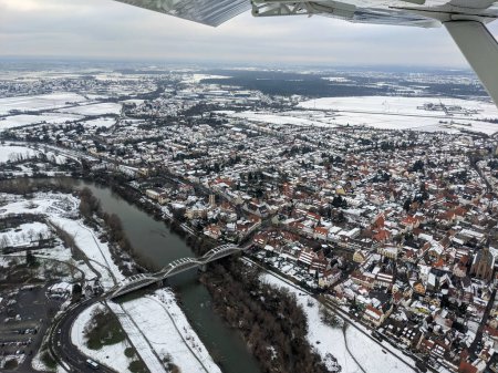 Téléchargez les photos : Vue aérienne de la rivière Neckar et du pont de Seckenheim (Mannheim) durant l'hiver couvert de neige. Avion léger survolant la ville après le départ de l'aéroport régional. - en image libre de droit