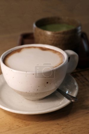Foto de Café con leche caliente con té verde matcha caliente en mesa de madera - Imagen libre de derechos