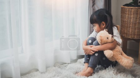 Photo for Close up lonely little girl hugging toy, sitting at home alone, upset unhappy child waiting for parents, thinking about problems, bad relationship in family, psychological trauma - Royalty Free Image