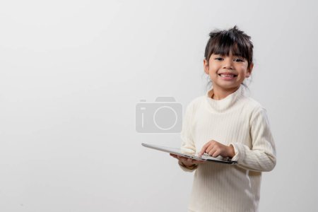 Asian little girl holding and using the digital tablet on white studio background, free copy space