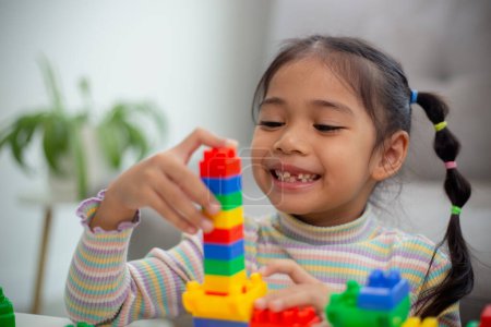 Photo for Adorable little girl playing toy blocks in a bright room - Royalty Free Image