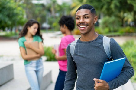 Lachender afrikanisch-amerikanischer Student mit einer Gruppe brasilianischer junger Erwachsener im Freien in der tropischen Stadt