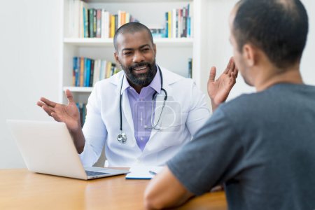 Photo for Handsome mature adult african american male doctor talking to patient at office of hospital - Royalty Free Image