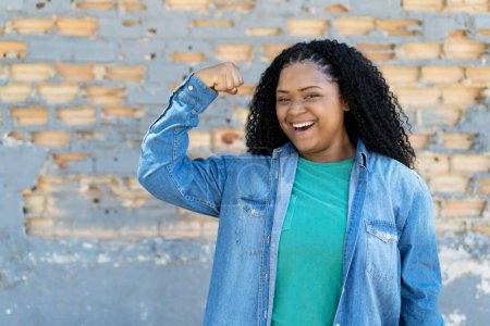 Téléchargez les photos : Successful cheering black young adult woman outdoor in city - en image libre de droit
