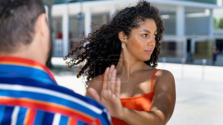 Téléchargez les photos : Femme latino-américaine geste arrêt à petit ami dans la discussion en plein air en ville en été - en image libre de droit