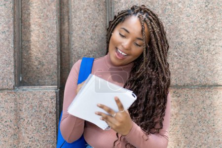 Photo for Smart black female student with dreadlocks writing notes in front of university building outdoor in city - Royalty Free Image