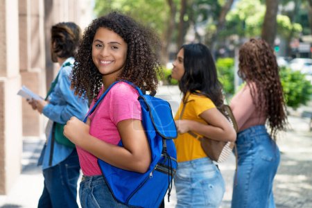 Junge hispanische Studentin mit einer Gruppe kaukasischer und afrikanisch-amerikanischer junger Erwachsener im Sommer in der Stadt