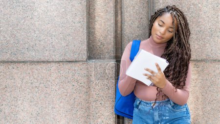 Photo for Serious african american female university student with backpack writing notes outdoors with copy space - Royalty Free Image