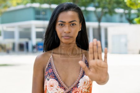 Téléchargez les photos : Femme sud-américaine avec des vêtements traditionnels geste arrêt avec la main en plein air en été en ville - en image libre de droit