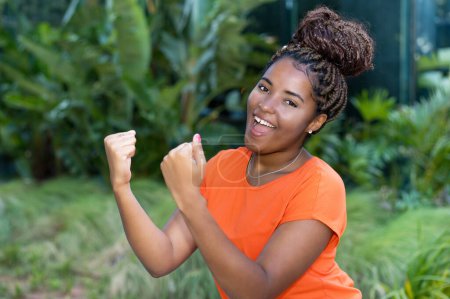 Téléchargez les photos : Santé jeune femme adulte d'Afrique avec chemise orange dans une zone tropicale - en image libre de droit