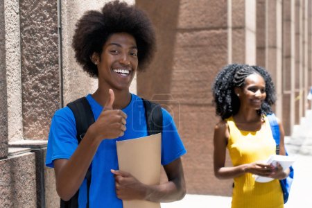 Photo for Successful african american male student with black female student in background outdoor on street in city in summer - Royalty Free Image