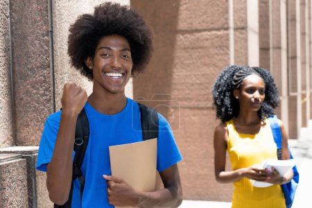 Photo for Cheering african american male student with black female student in background outdoor on street in city in summer - Royalty Free Image