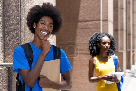 Photo for Handsome african american male student with black female student in background outdoor on street in city in summer - Royalty Free Image