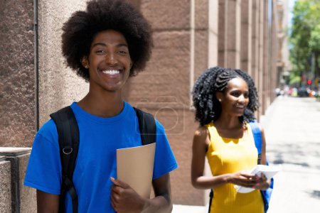 Photo for Laughing african american male student with black female student in background outdoor on street in city in summer - Royalty Free Image