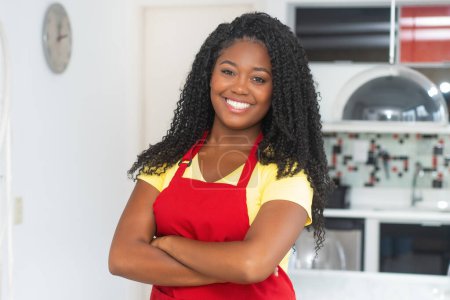 Photo for Portrait of  beautiful african american woman with apron indoors at modern kitchen - Royalty Free Image