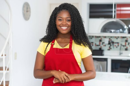Photo for Portrait of  african american woman with apron indoors at modern kitchen - Royalty Free Image