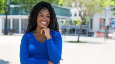 Téléchargez les photos : Rire femme afro-américaine avec un espace de copie dans la ville par une journée ensoleillée en été - en image libre de droit