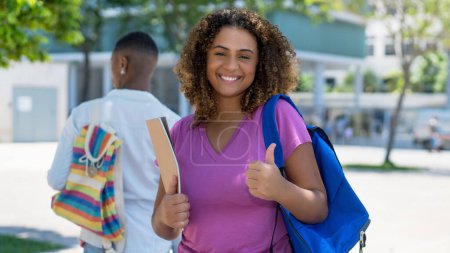 Photo for Successful hispanic female student with backpack and paperwork infront of university outdoor in summer in city - Royalty Free Image
