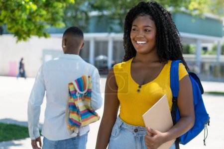 Photo for Beautiful black female student with backpack and male student in background outdoor in summer in city - Royalty Free Image