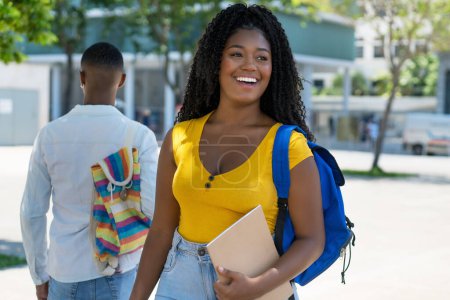 Photo for Pretty black female student with backpack and male student in background outdoor in summer in city - Royalty Free Image