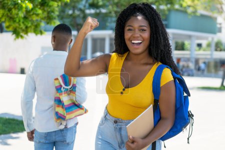 Animando a una estudiante afroamericana con un exitoso resultado de prueba al aire libre en verano en la ciudad