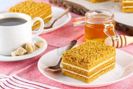 Téléchargez les photos : Homemade Honey cake. Honey cake Medovik, layer cake on white plate. Closeup view. sweet dessert cake. Slice of layered honey cake selective focus. - en image libre de droit