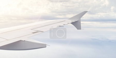 Téléchargez les photos : Vue de l'aile de l'avion fenêtre de la rue dans le ciel. Nuages et ciel vus à travers le hublot d'un aéronef à aile d'avion - en image libre de droit