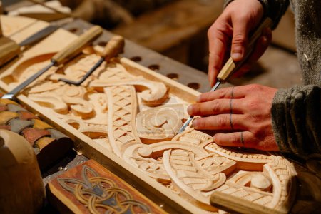 Dieses Bild zeigt einen erfahrenen Tischlermeister, der sorgfältig kunstvolle und komplizierte Muster auf einer Holzoberfläche schnitzt, was die Kunstfertigkeit und Präzision der Holzbearbeitung unterstreicht..