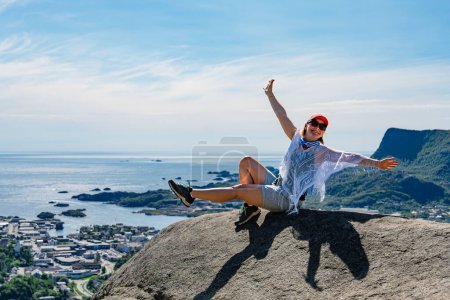 Téléchargez les photos : Un groupe d'explorateurs debout sur un sommet de montagne, regardant les vues à couper le souffle sur le paysage norvégien alors que le soleil se couche derrière les montagnes majestueuses. - en image libre de droit