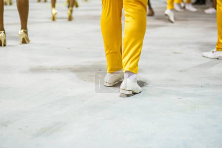 Téléchargez les photos : Legs of a sambista dancing, with yellow pants and white shoes at the sambodromo da marques de sapucai in Rio de Janeiro, Brazil. - en image libre de droit