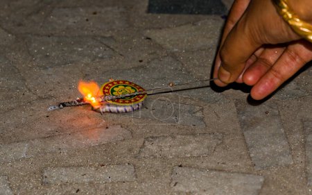 Photo for Igniting ground spinner with the help of sparkler during diwali - Royalty Free Image