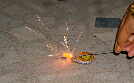 Photo for Igniting ground spinner with the help of sparkler during diwali - Royalty Free Image