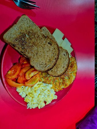 Bild vom Frühstücksteller mit haschbraunem Brot, gerösteten Tomaten-Rührei