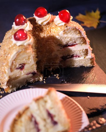 Foto de Pastel alemán Frankfurter Kranz o Frankfurt Crown Cake en mantel de lino azul oscuro. Otoño, hojas amarillas de otoño. DOF superficial, concéntrate en la mitad del pastel sin cortar. - Imagen libre de derechos