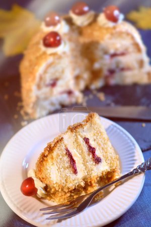 Photo for German cake Frankfurter Kranz or Frankfurt Crown Cake on dark blue linen tablecloth. Autumntime, yellow Fall leaves. Blurred half of the cake. Shallow DOF, focus on the piece of cake in front. - Royalty Free Image